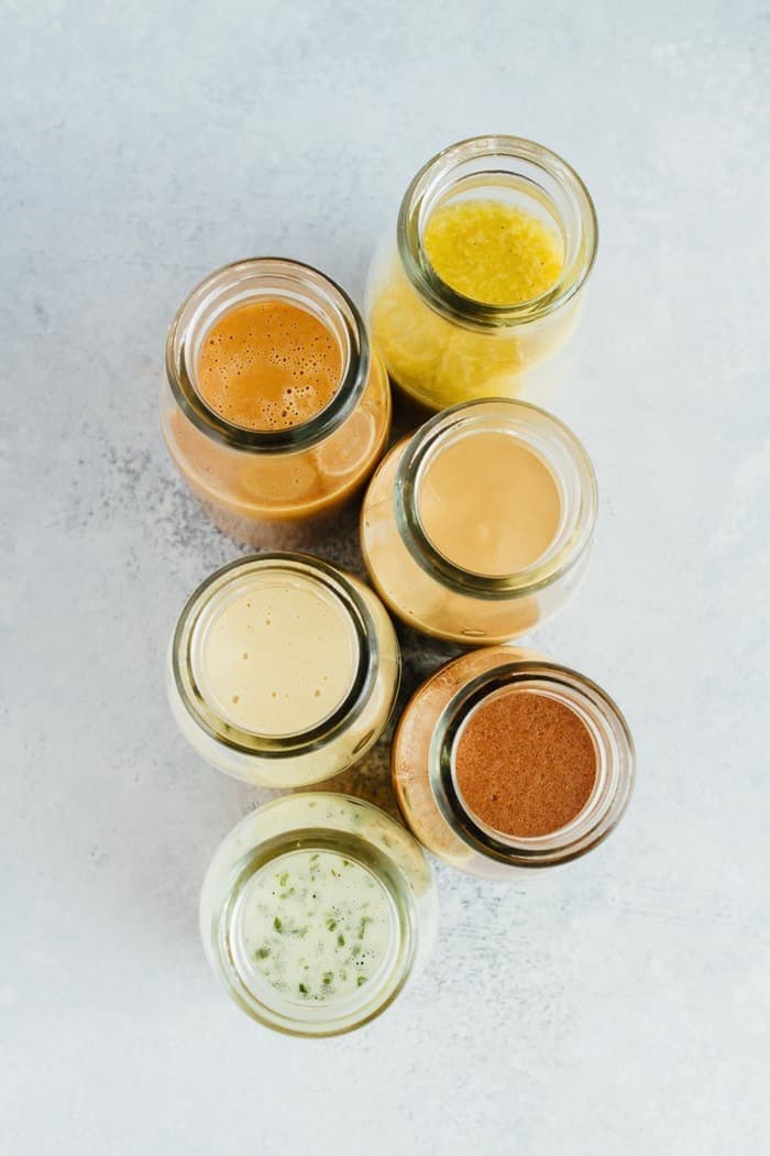 PIN THIS --> 6 HEALTHY homemade salad dressings that are super easy to make! 6 homemade dressings in glass jars on a gray countertop.