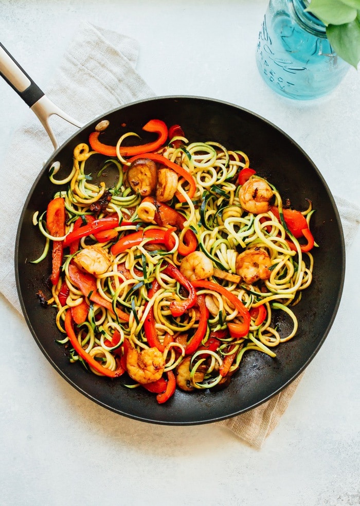 Cooked shrimp and zucchini noodle lo mein in a large skillet.