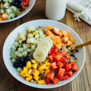 A quinoa breakfast bowl topped with a variety of fresh fruit.