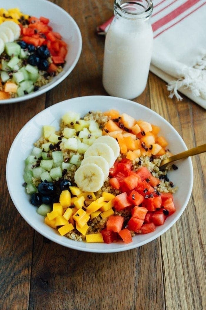 A quinoa breakfast bowl topped with a variety of fresh fruit.