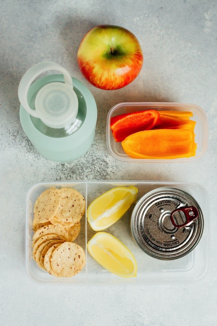 No time to pack lunch? Try this simple lemony tuna salad recipe you can make at your desk. Just add lemon juice, salt and pepper! Eat plain or serve with crackers and veggies. A can of tuna in a plastic container with lemon slices, crackers and bell peppers.