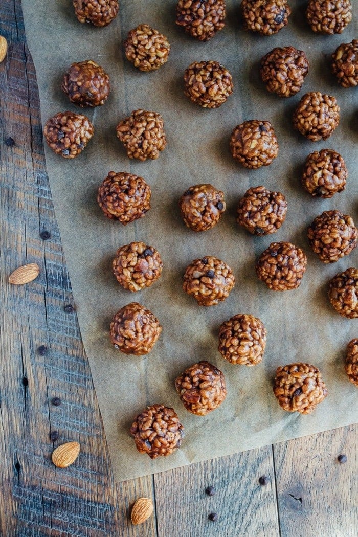 These chocolate almond crispy bites are dangerously good and made with only 5 ingredients. Perfect for kids (and adults), plus they’re vegan and gluten-free. Chocolate almond crispy bites spread across a sheet of brown parchment paper.