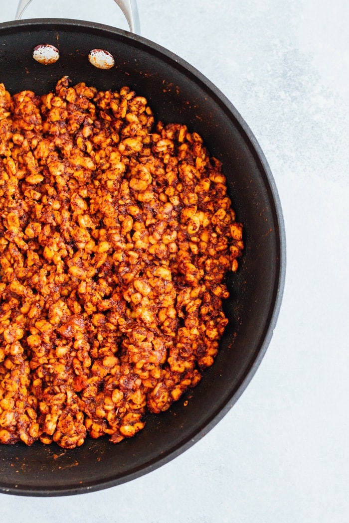 Tempeh Taco Salad Meal Prep Bowls with tempeh taco meat, black beans, tomatoes, onions and avocado A seasoned tempeh mixture being cooked in a skillet.