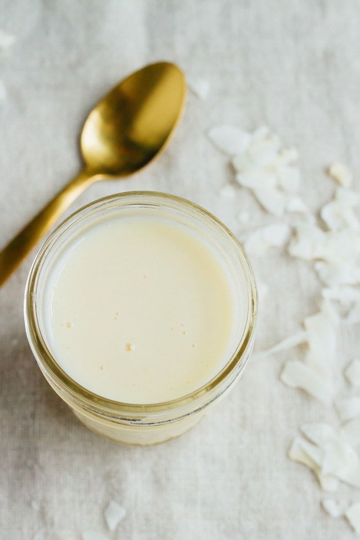 Coconut butter in a small mason jar with a gold spoon on the left.