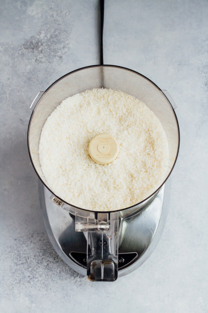 Shredded coconut in the food processor getting ready to be turned into coconut butter.
