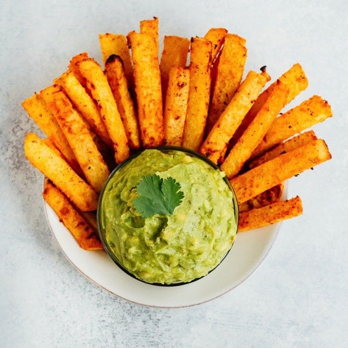 PIN THIS--> Baked Jicama Fries Jicama french fries served in a bowl with a guacamole dip in the center.