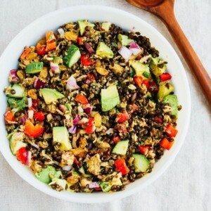 A large bowl of lentil tuna salad with a wooden serving spoon to the side of the bowl.