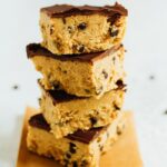 Four cookie dough bars stacked on each other all with a chocolate coating that tops them off.