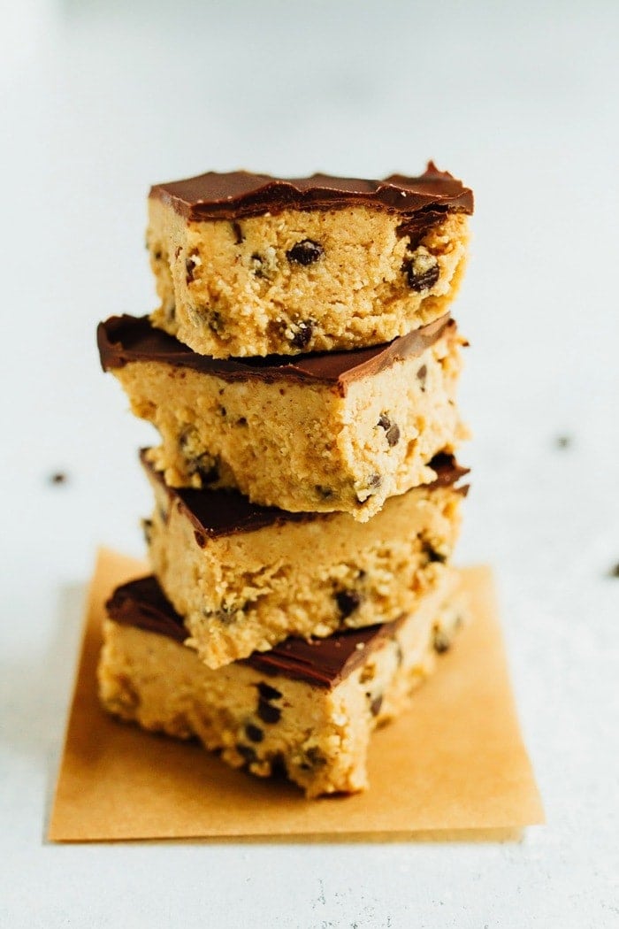 No Bake VEGAN GLUTEN-FREE Cookie Dough Bars Four cookie dough bars stacked on each other all with a chocolate coating that tops them off.