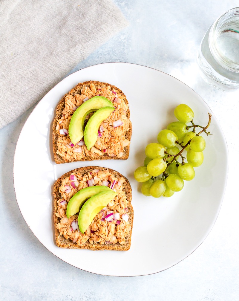 Combine hummus and bbq sauce with canned tuna for a sweet and savory open-faced bbq hummus tuna sandwich. It’s easy, healthy and absolutely delicious! Two slices of bread on a plate with tuna salad, and sliced avocado, and a side of green grapes.