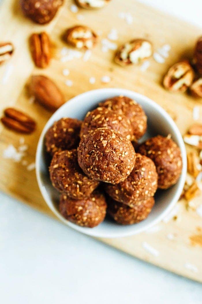 Overhead photo of German Chocolate Energy Bites with Pecans served in a white bowl on wood cutting board.