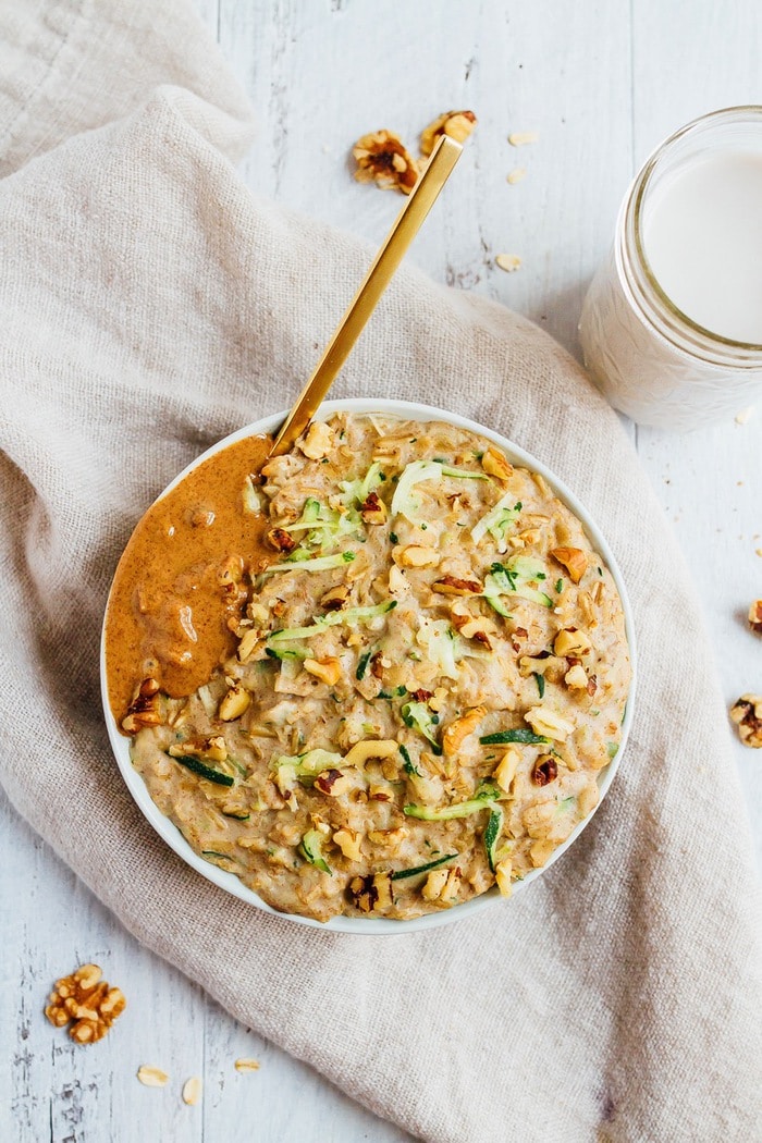 Add veggies and volume to your morning bowl of oats with this zucchini bread oatmeal recipe. It's hearty, filling and will keep you energized all morning! Bowl of zucchini bread oatmeal topped with walnuts and almond butter.