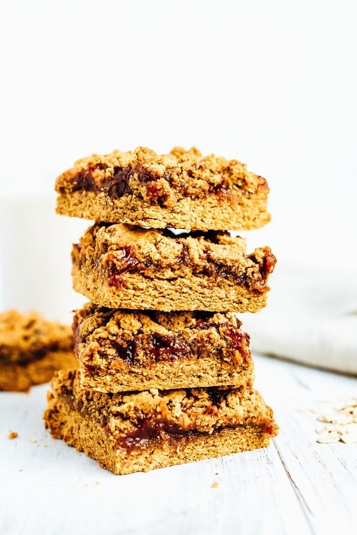 These PB&J Bars are a take on the classic sandwich we all know and love. Made with protein-packed peanut powder, oat flour, organic jam and coconut oil, you can feel good about enjoying these bars whenever you please. Stack of four pb&j bars. Bars filled with jam, topped with peanut butter crumble.