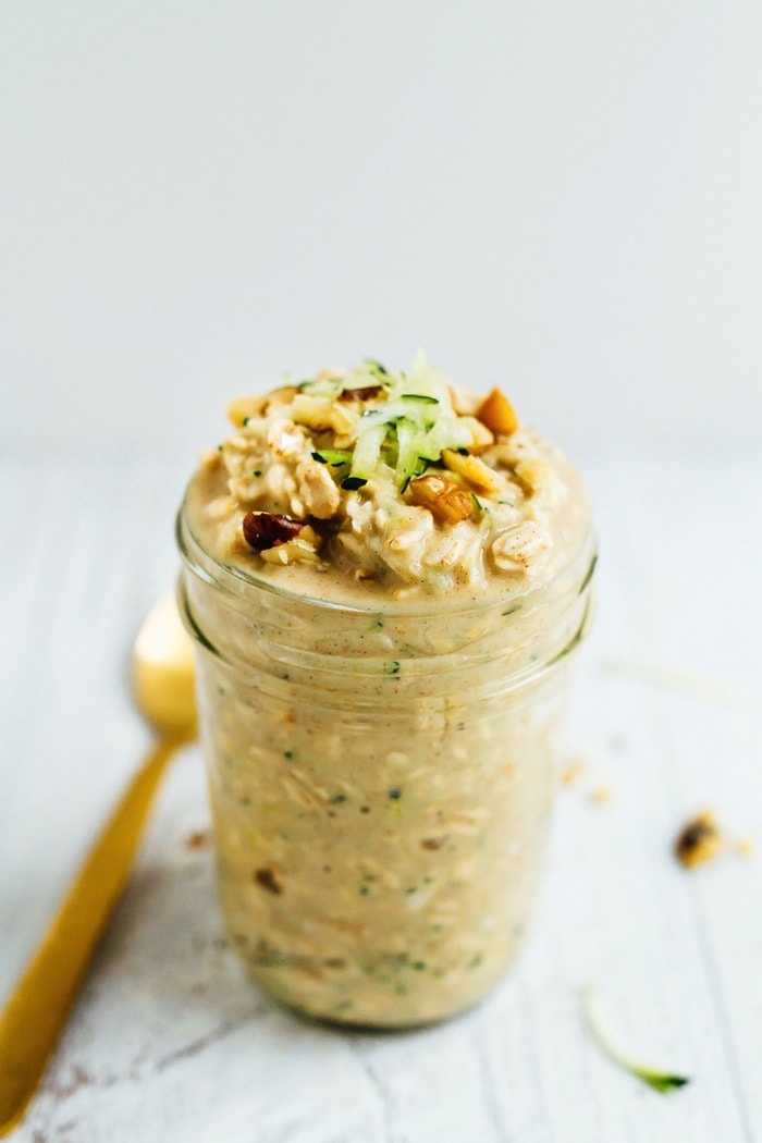 Zucchini bread overnight oats make for an easy and healthy portable breakfast. Made with oats, protein powder, grated zucchini and walnuts, these overnight oats are vegan and gluten-free. A serving of zucchini bread overnight oats in a mason jar topped with shaved zucchini and crushed walnuts.
