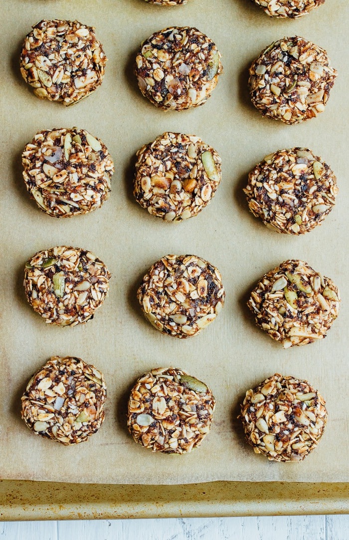 Eat like a bird with these BIRD FOOD ENERGY BITES! Made with whole grain oats, nuts, seeds and dried fruit, these bites are a nutrient-rich treat perfect for on-the-go snacking. Vegan + gluten-free. Granola bites unbaked in lines on parchment on a baking tray.