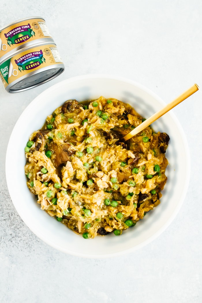 A healthy spin on a comfort food classic, these spaghetti squash tuna noodle casserole boats are filled with loads of creamy noodle goodness. Gluten-free, dairy-free, low-carb and paleo! Tuna casserole with peas is served in a bowl with a spoon. Two cans of Genova albacore tuna are off to the side.