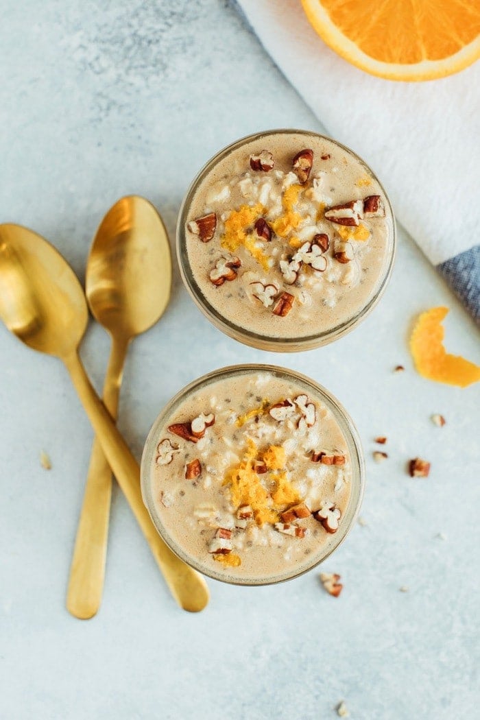 Orange Vanilla Overnight Oats // Vegan + Gluten-Free Two glass jars served with overnight oats and topped with crushed pecans and orange zest.