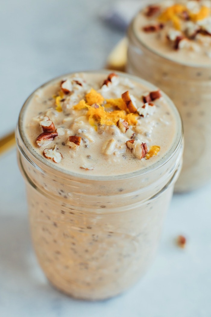 Orange Vanilla Overnight Oats // Vegan + Gluten-Free A serving of a vanilla orange overnight oats in a glass mason jar topped with orange zest and crushed pecans.
