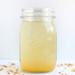 A glass mason jar containing a ginger spice apple vinegar drink.