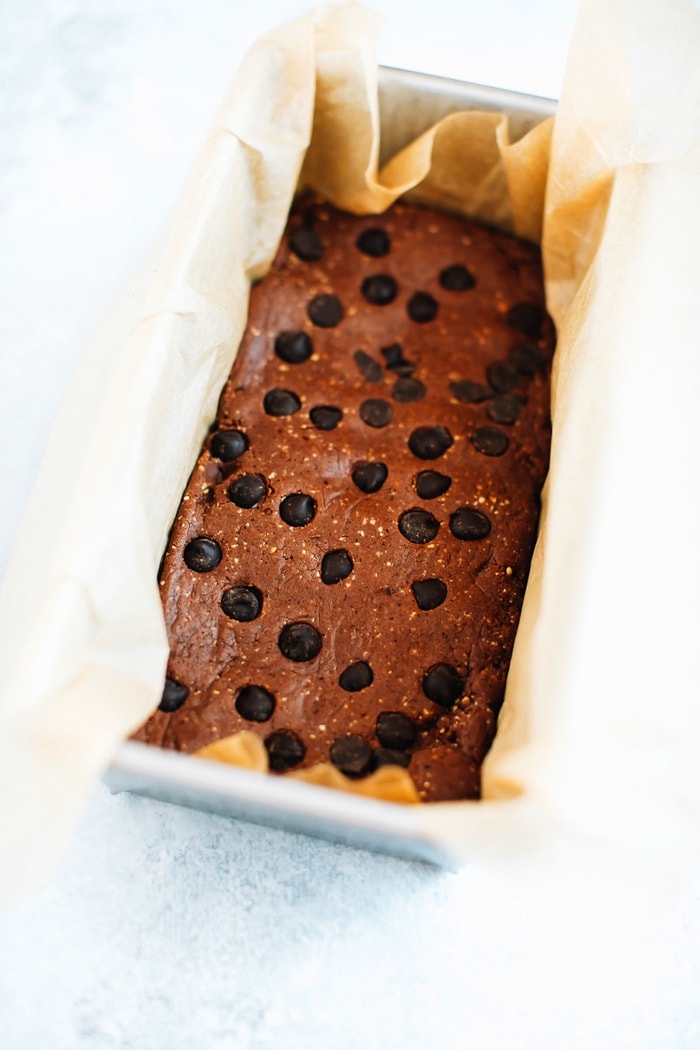 Pin this recipe for Homemade Peanut Butter Chocolate Protein Bars! Protein bars in a loaf pan with parchment.