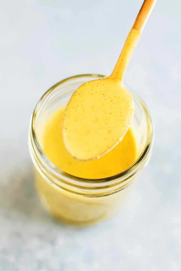 A super simple recipe for an anti-inflammatory turmeric tahini dressing that’s the perfect topping for your favorite salad, but also lovely as a sauce or dip! A spoonful of turmeric tahini dressing over a mason jar of the dressing.