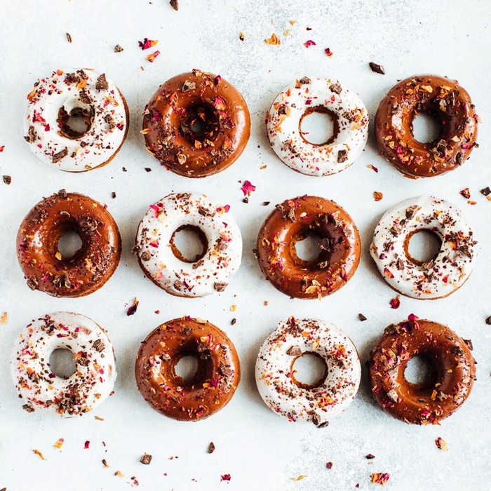 Perfect for Valentine’s Day, these baked almond flour donuts with rose petals and dark chocolate are gluten-free, dairy-free and naturally sweetened with coconut sugar. A dozen baked almond flour donuts with half having a chocolate coating and the other half with a vanilla coating.