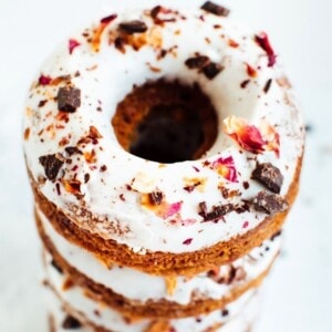 A stack of almond flour donuts topped with chocolate and rose petals.