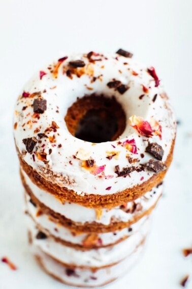 A stack of almond flour donuts topped with chocolate and rose petals.