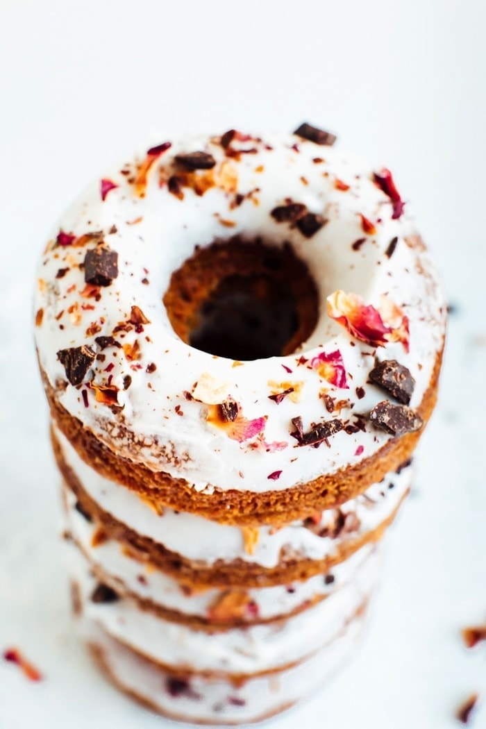 Perfect for Valentine’s Day, these baked almond flour donuts with rose petals and dark chocolate are gluten-free, dairy-free and naturally sweetened with coconut sugar. A stack of almond flour donuts topped with chocolate and rose petals.