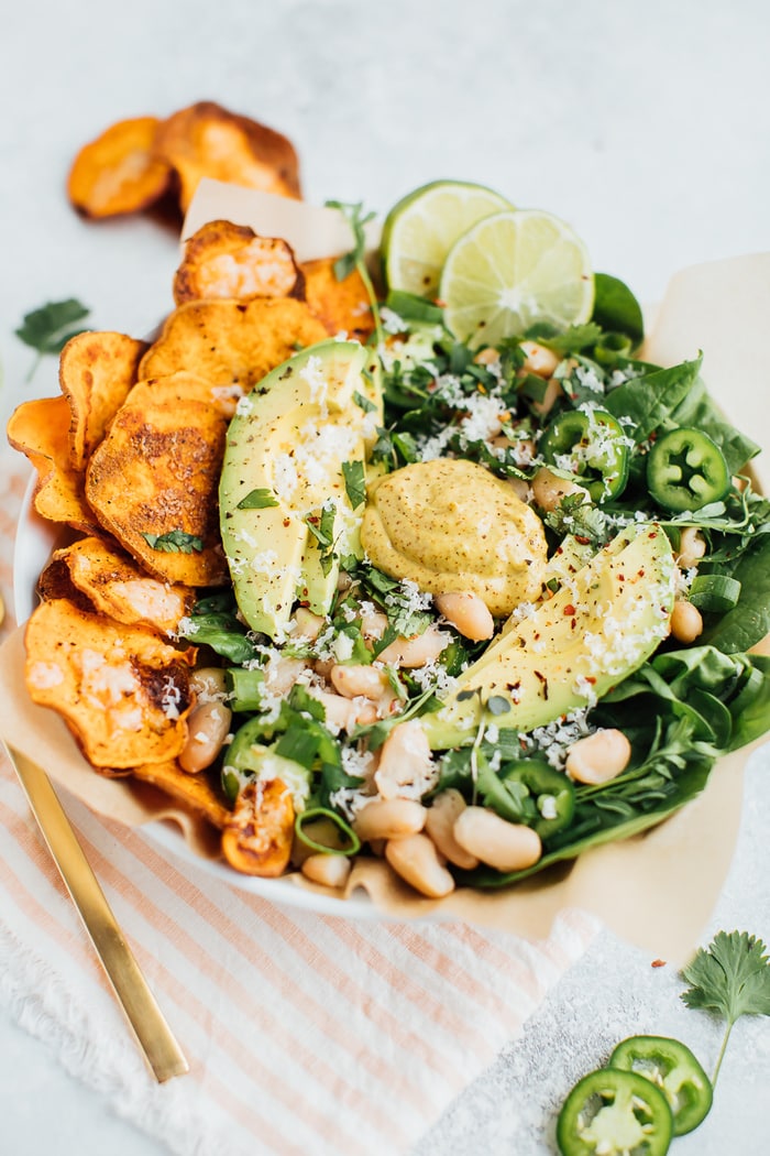 Loaded sweet potato nacho salad bowls with sweet potato chips, baby spinach, jalapeño and fresh herbs. 
