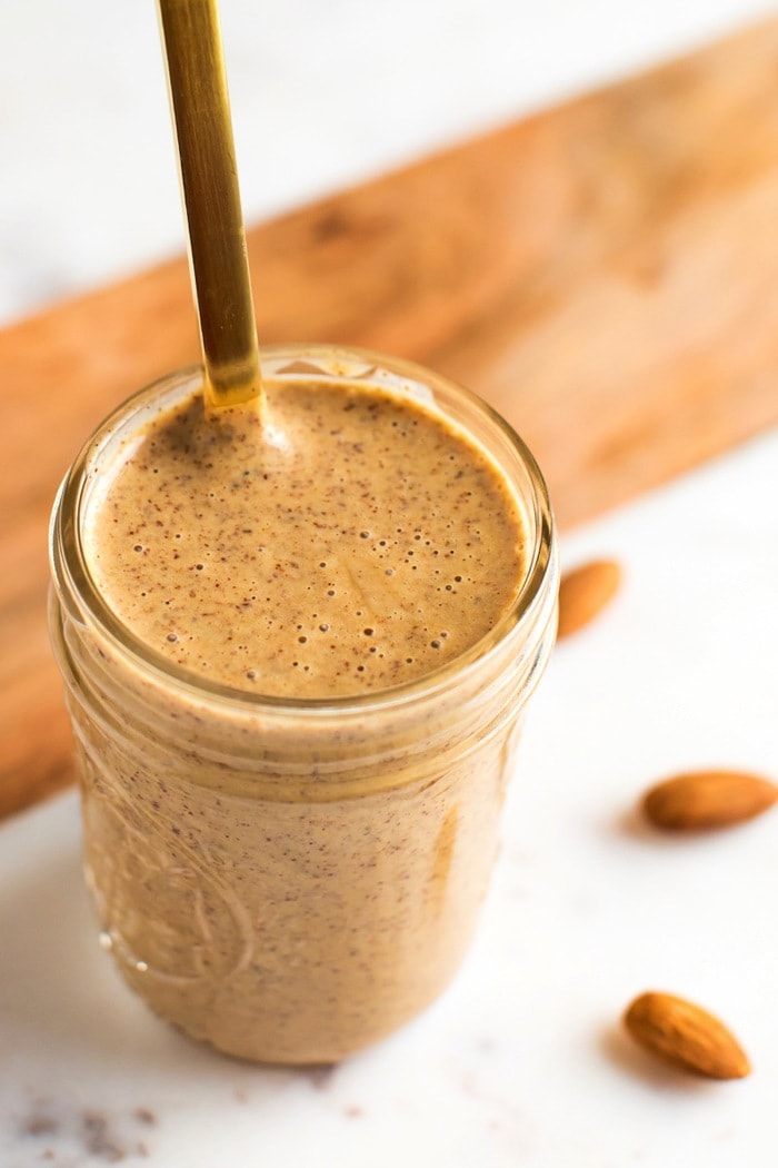 PIN THIS --> Chili Almond Dressing Almond dressing in a mason jar with gold spoon.