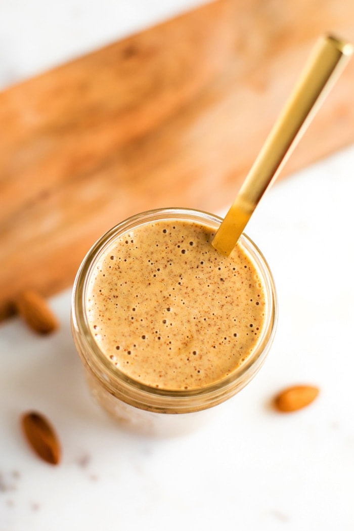 PIN THiS --> Chili Almond Dressing Chili almond dressing a small mason jar with gold spoon. Almonds in background.