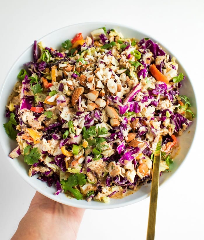 PIN THIS --> Asian Chopped Salad Crunchy asian salad in a white bowl with gold spoon being held by a woman's hand.