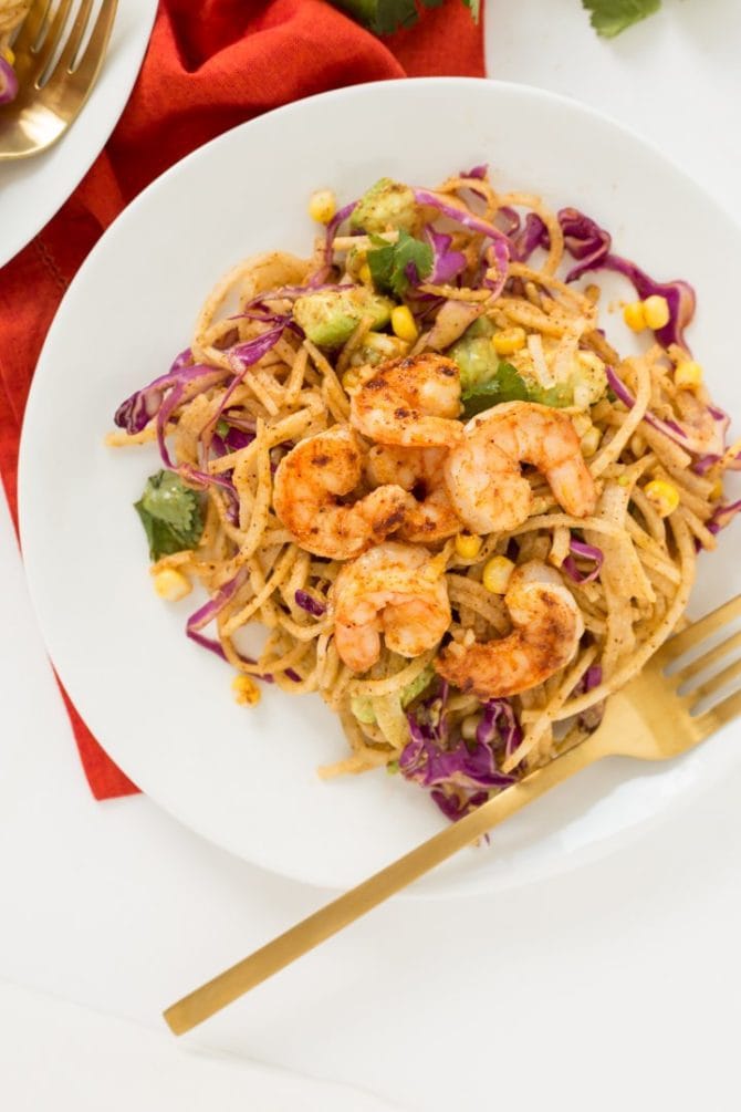 PIN THIS--> 12 Healthy Jicama Recipes Chili lime shrimp and corn on top of a plate of spiralized jicama noodles. A gold folk in resting on the plate.