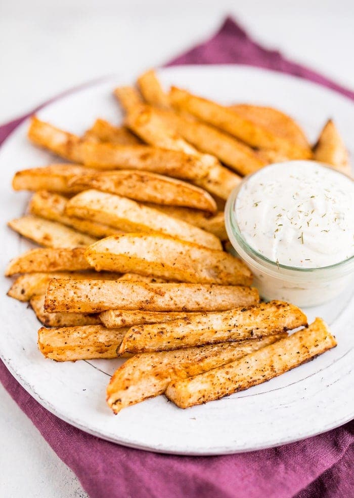 PIN THIS--> Baked Turnip Fries White plate piled with turnip fries and a greek yogurt ranch dip in a glass jar.