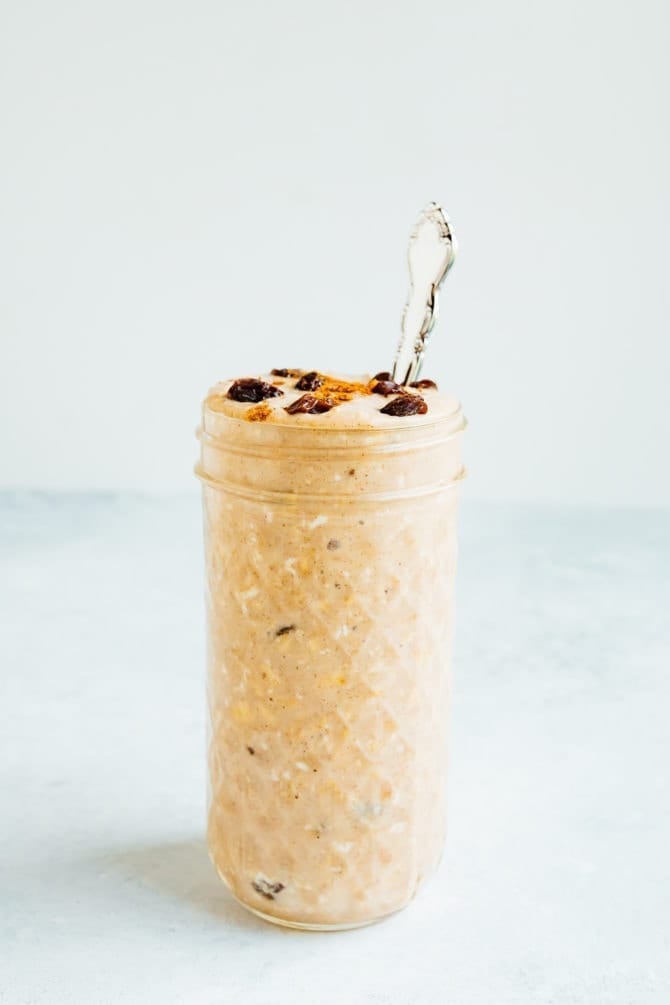PIN THIS--> Cinnamon Raisin Overnight Oats Tall glass jar filled with cinnamon raisin overnight oats, toped with a sprinkle of cinnamon and raisins. Silver spoon in the jar.