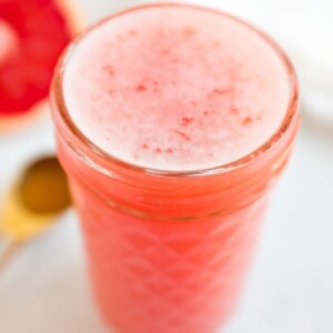 A glass jar with a grapefruit drink filled to the top.