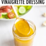 Spoon with a spoonful of apple cider dressing from a mason jar.