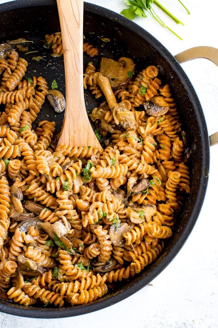 A skillet of healthy, protein-packed vegan mushroom stroganoff made with savory mushrooms, lentil pasta and a creamy coconut milk sauce.