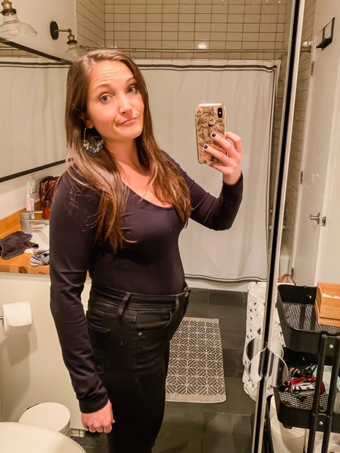 Hotel mirror selfie of woman with travel bloat.
