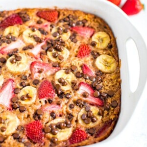 Baked oatmeal with fresh strawberries, banana and chocolate chips in a square baking dish.