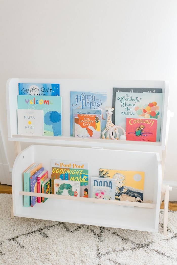 White and wood modern nursery bookshelf with children's books and toys.