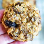 Hand holding a cinnamon raisin protein cookie.