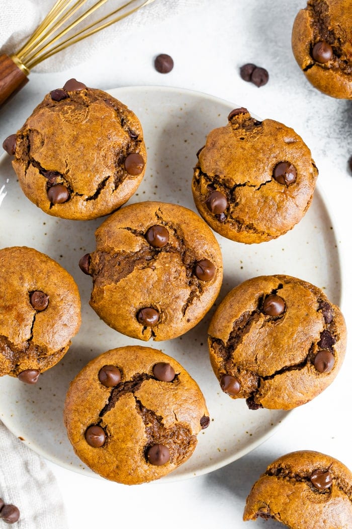 Six flourless pumpkin muffins with chocolate chips served on a large plate.