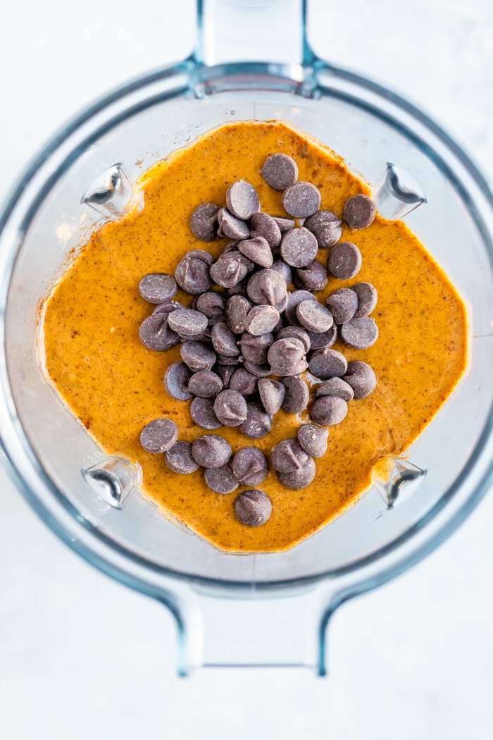 Overhead photo of a blender with flourless pumpkin batter and chocolate chips on top.