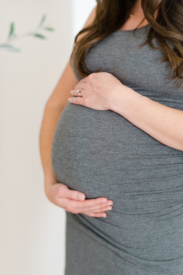 Up close photo of pregnant belly with woman's hands around it.