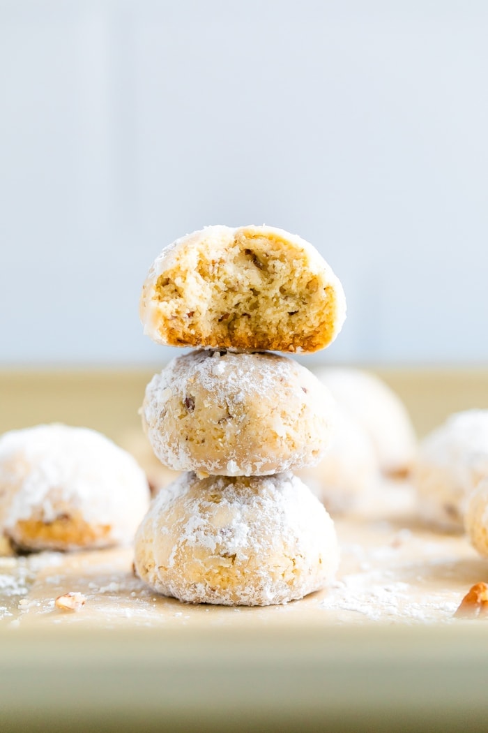 snowball cookies Stack of three snowball cookies on parchment paper. The top one has a bite taken out of it.