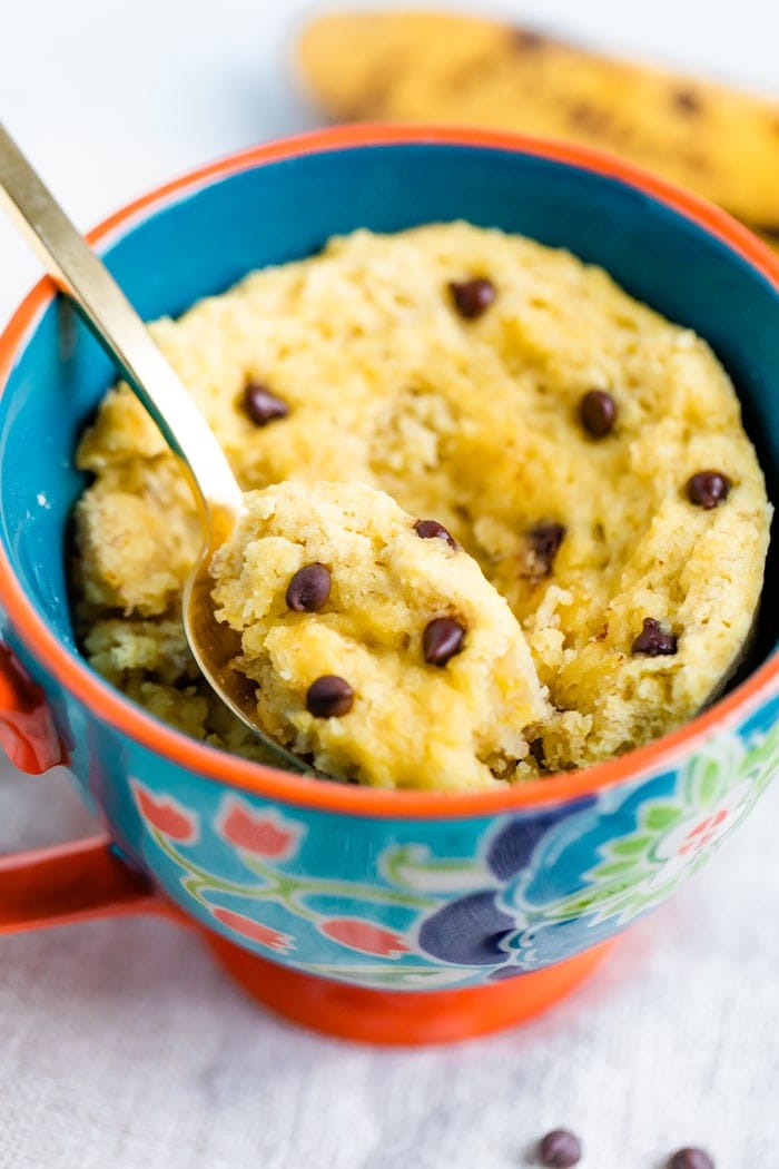Mug with a chocolate chip mug cake and a spoon scooping out a bite.