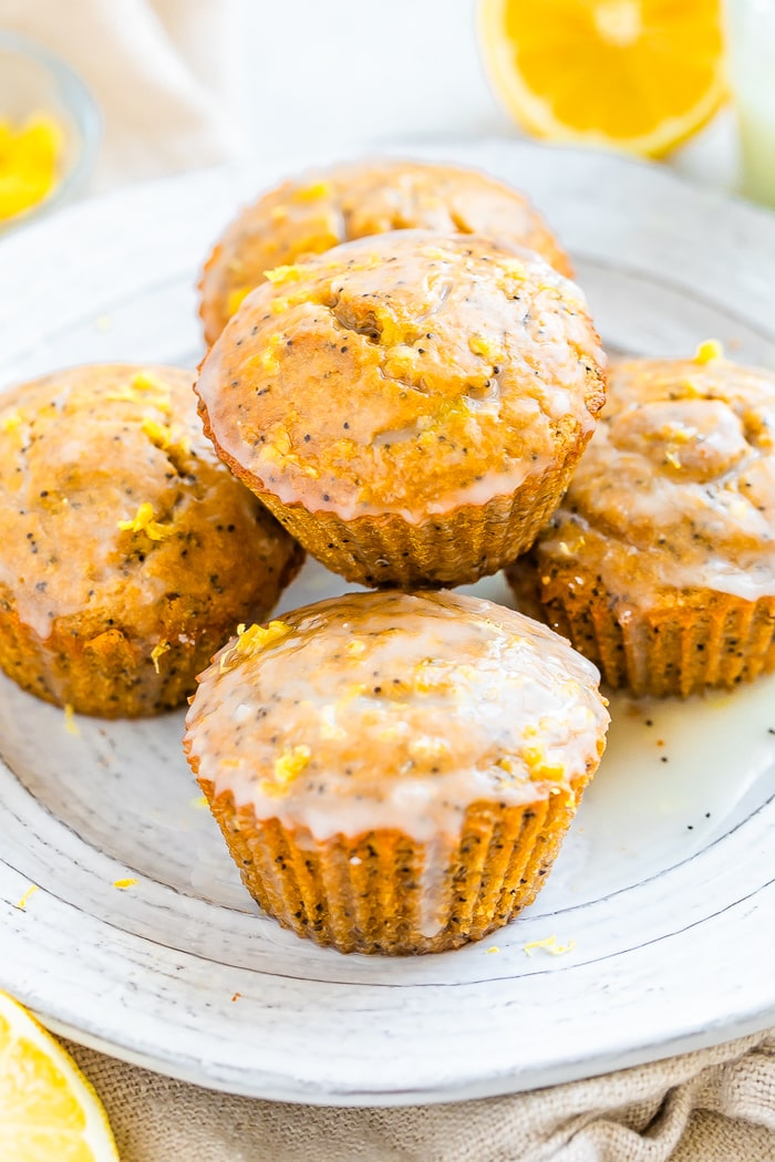 Plate piled with lemon poppyseed muffins topped with a glaze and lemon zest.