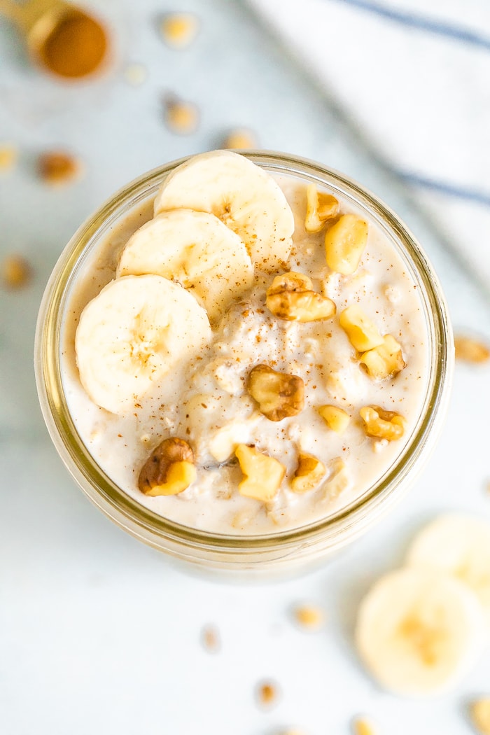 Overhead photo of a mason jar with banana bread overnight oats, topped with banana slices and walnuts.